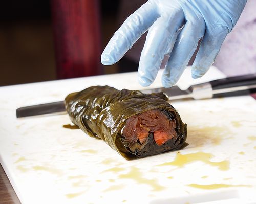 昆布巻(大根、しそ、きゅうり、にんじん、を昆布で巻いてます)の味噌漬けを切っています